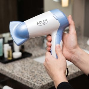 Zložen moder in črn potovalni sušilnik za lase na beli podlagi